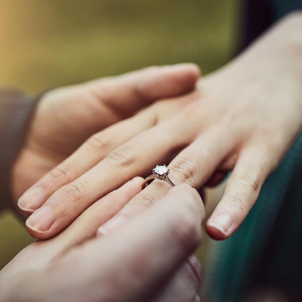 man putting engagement ring on woman's finger