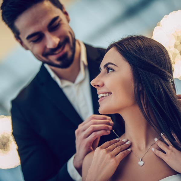 man putting necklace on woman